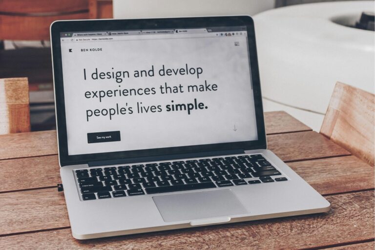 A laptop on a wooden table showing a web designer's home page