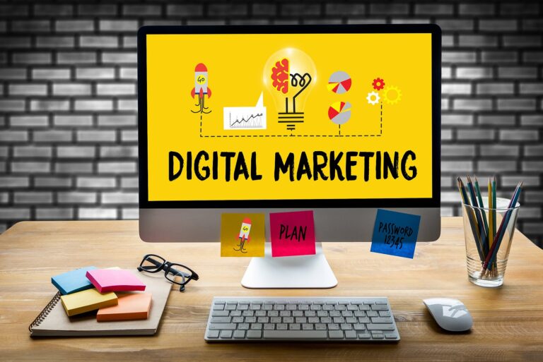 A desktop computer showing the words digital marketing on a desk with sticky notes and glasses