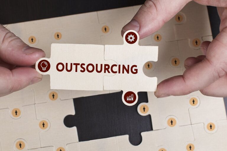 Two hands fitting together jigsaw pieces, one labelled outsourcing