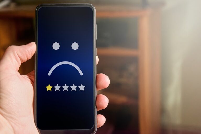 A hand holding a phone showing a sad face and a one-star rating