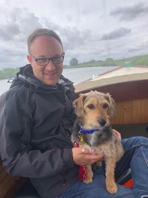 Matt Bryant on a boat with a small terrier on his lap