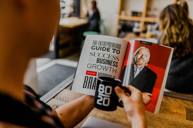 Someone holding a coffee mug while reading an entrepreneur's guide to business growth