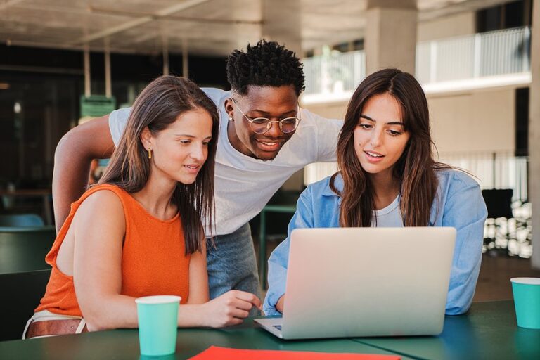 Three young people looking at a laptop together and smiling