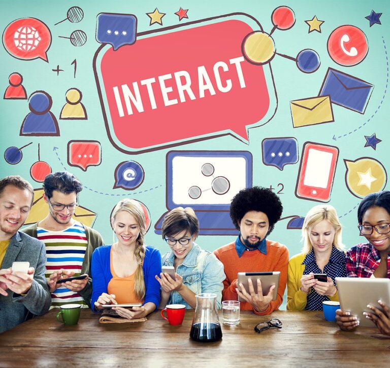 A group of people using phones and tablets at a table beneath social media icons and the word interact